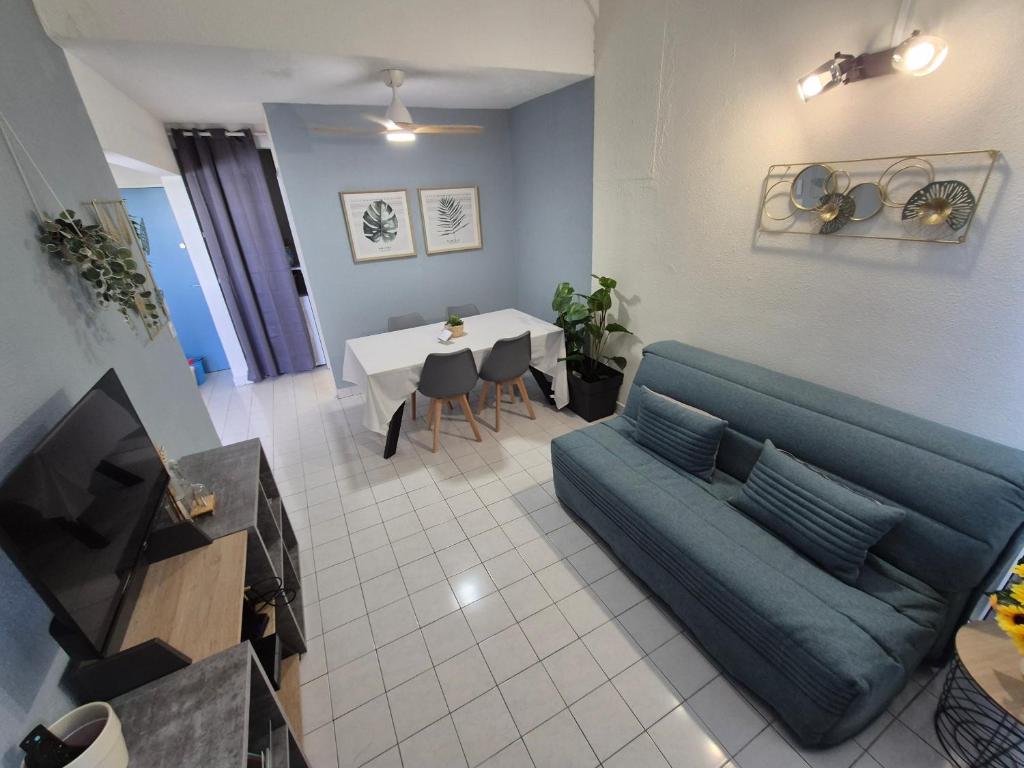 a living room with a blue couch and a table at Coeur Citadin - 4 personnes - Plein Centre Ville 2eme étage in Saint-Denis