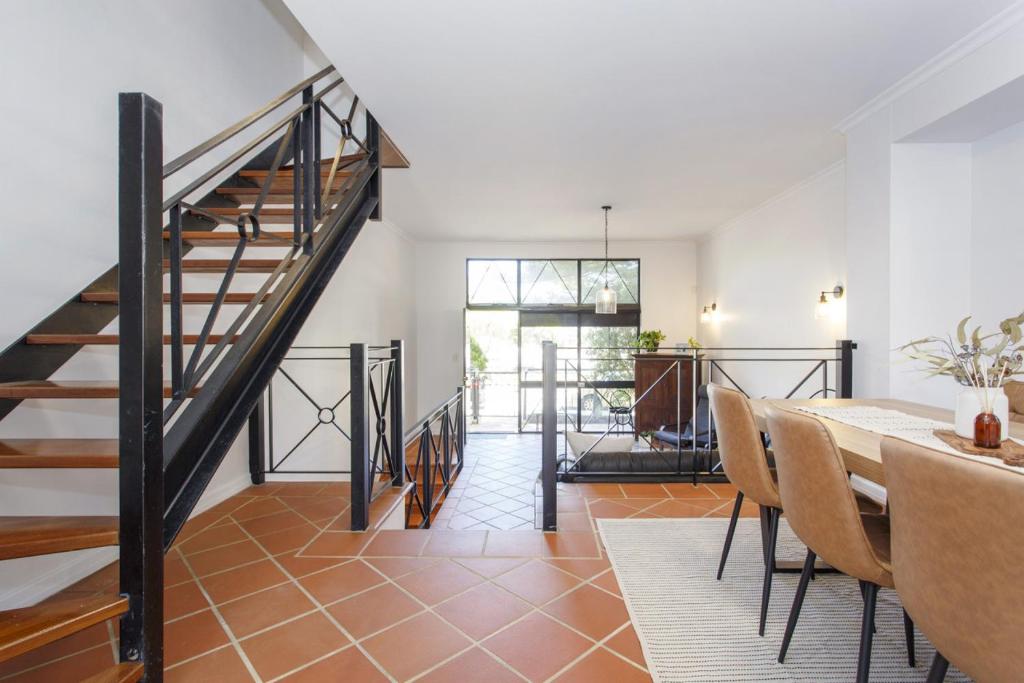 Un comedor con escalera y mesa y sillas. en Terrace Heaven - Luxe Retreat in Fremantle, en Fremantle