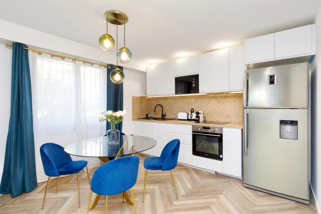 une cuisine avec une table en verre et des chaises bleues dans l'établissement Bel appartement Port de Nice avec terrasse, parking, à Nice