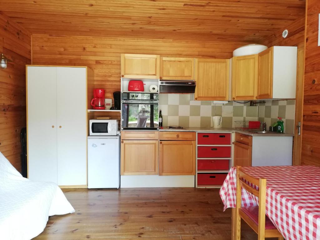une cuisine avec des armoires en bois et un réfrigérateur blanc dans l'établissement La Cabane d'Oza, à Saint-Pierre-dels-Forcats
