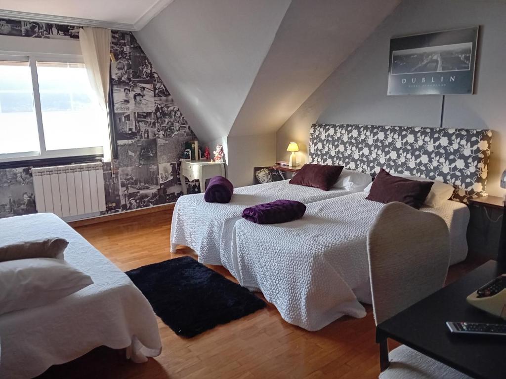 una camera con 2 letti con lenzuola bianche e cuscini viola di Casa Ana a Redondela