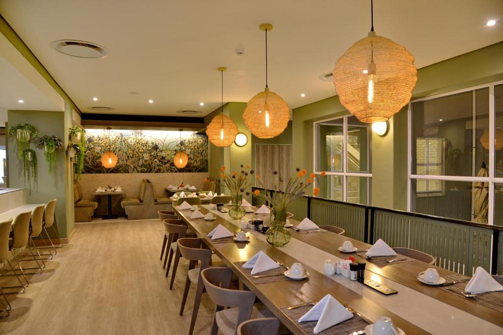 a restaurant with long tables and chairs and lights at Town Lodge Bellville in Bellville