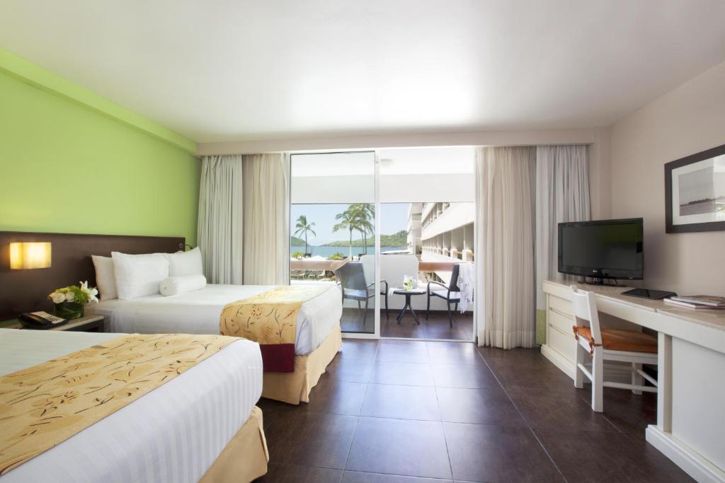 a hotel room with two beds and a television at Emporio Mazatlan in Mazatlán