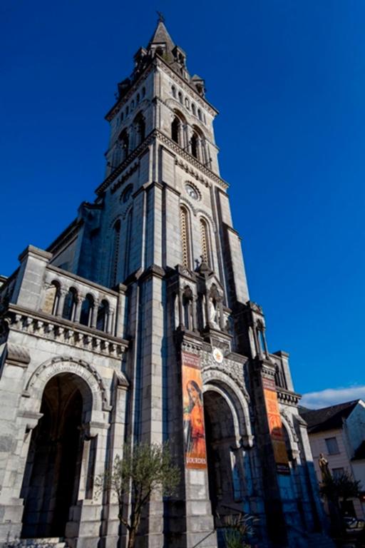 un grand bâtiment avec une tour dotée d'une horloge. dans l'établissement VUE DE REVE chambre dans APPARTEMENT DE STANDING - vous faites le ménage-Very good prices but you have to cle-an th-e flat, à Lourdes