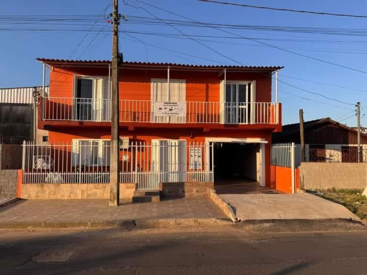 an orange house with a balcony on the side of it at Pousada Habitacion Aurora 3 in São Gabriel
