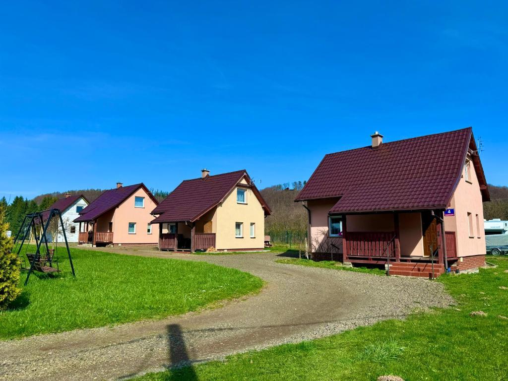 een rij huizen met een speeltuin in het gras bij Domki Letniskowe Konik 3 in Radków