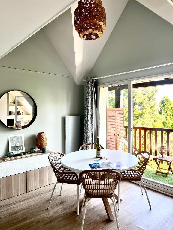 une salle à manger avec une table et des chaises blanches dans l'établissement Charmant Duplex entre Terre et Mer proche Plage avec Balcon, à Cabourg