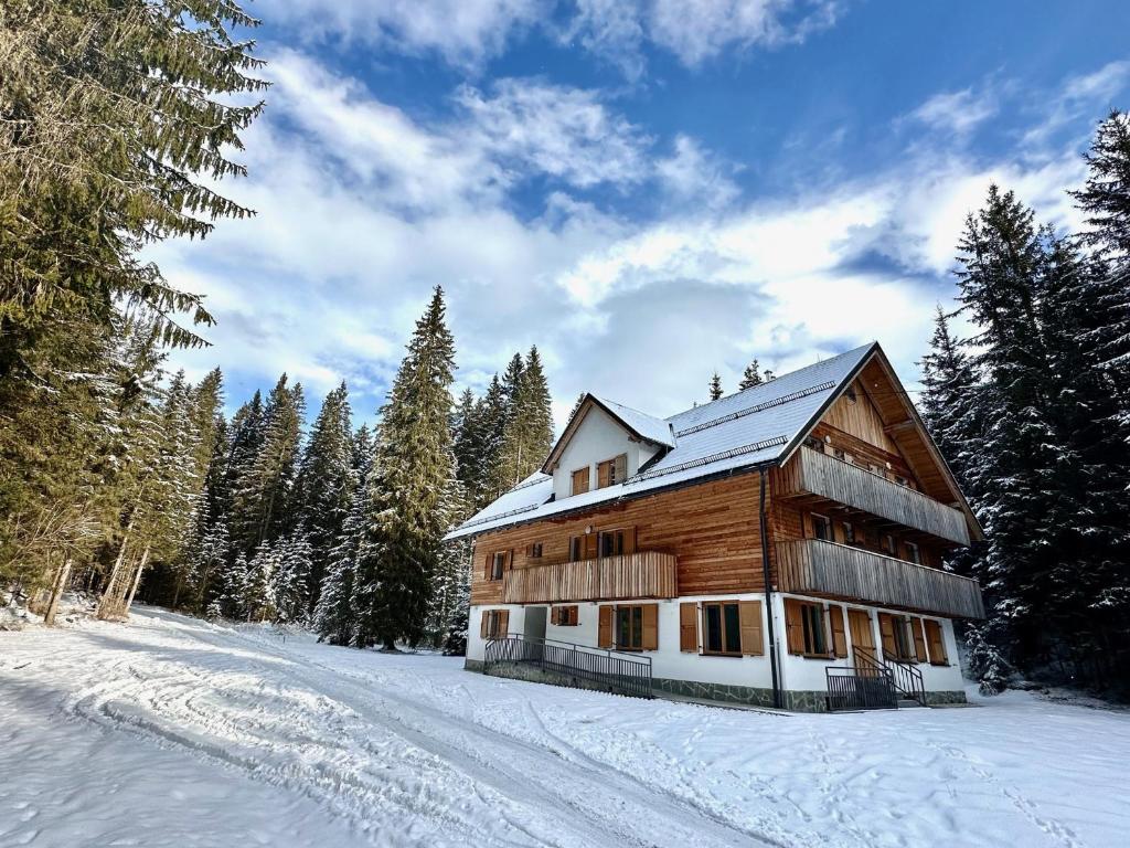 ゴレンスカ地方にあるPenzion Golcarの雪の中の木々の丸太小屋