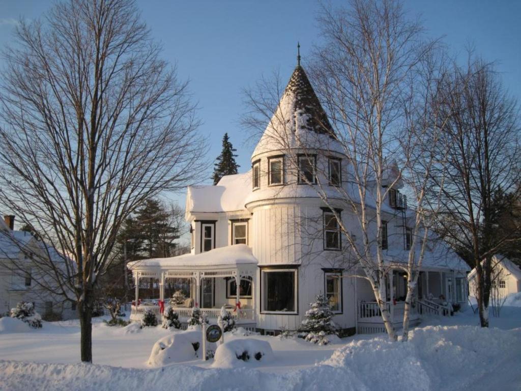 Glynn House Inn في Ashland: بيت ابيض كبير مع برج في الثلج