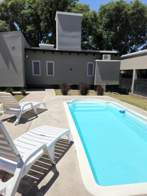 a swimming pool with two lounge chairs and a house at Casa de los Cerros I - Vaqueros in Vaqueros