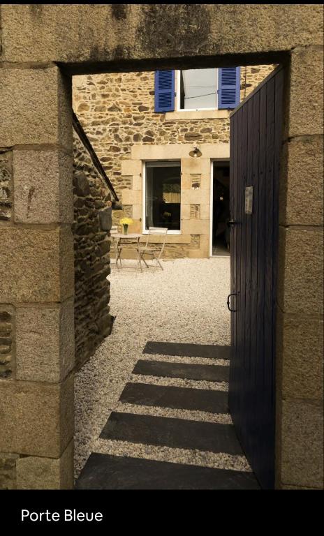 un accès à un bâtiment en pierre avec une porte noire dans l'établissement Maison de vacances bord de mer tout à pied, à Binic