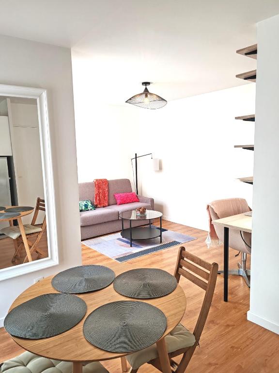 une chambre avec une table et des chaises ainsi qu'un salon dans l'établissement Le Cocon Stade de France - Aux Portes de Paris - Parking Inclus, à Saint-Denis