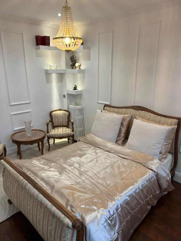 - une chambre avec un lit, une chaise et un lustre dans l'établissement Charming Stay, à Saint-Ouen