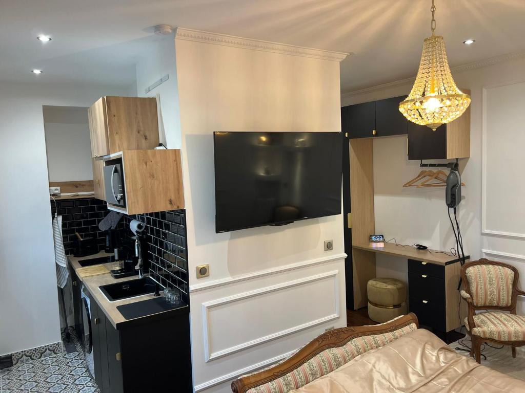 a living room with a kitchen with a flat screen tv at Charming Stay in Saint-Ouen