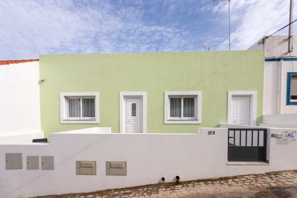 a green and white building with white walls at Casa da Colina in Ferragudo