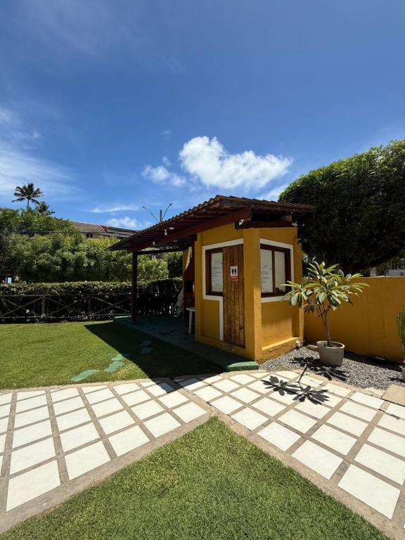 a small yellow house with a grass yard at Merepe Residence in Porto De Galinhas