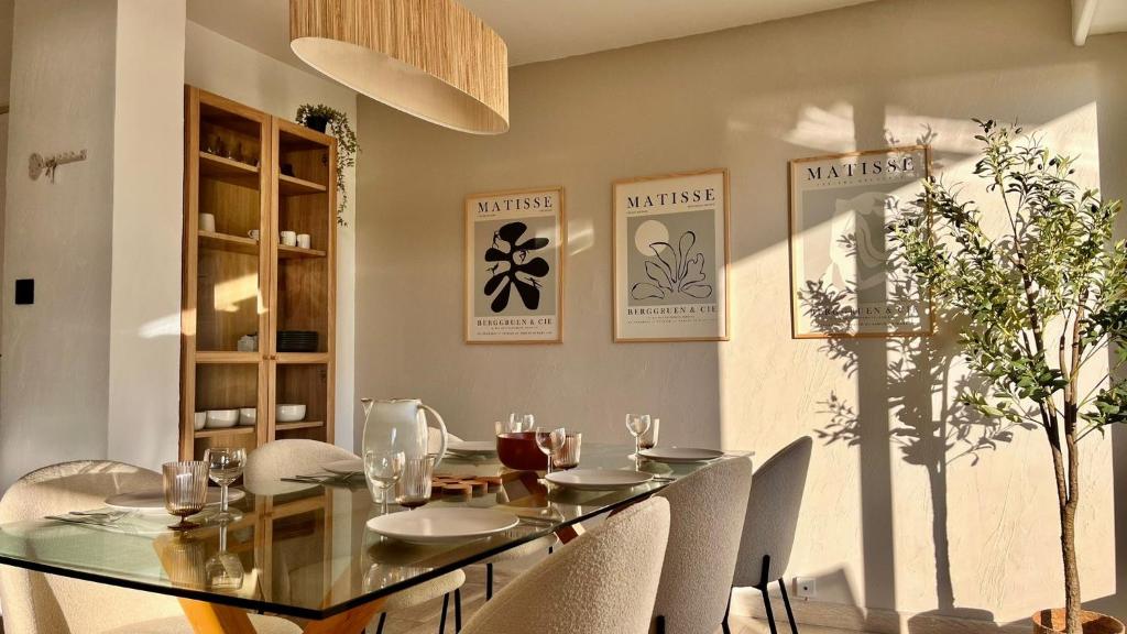 une salle à manger avec une table en verre et des chaises blanches dans l'établissement L Olivier - Vue mer - Clim - Piscine - Tennis - 6p, à Nice