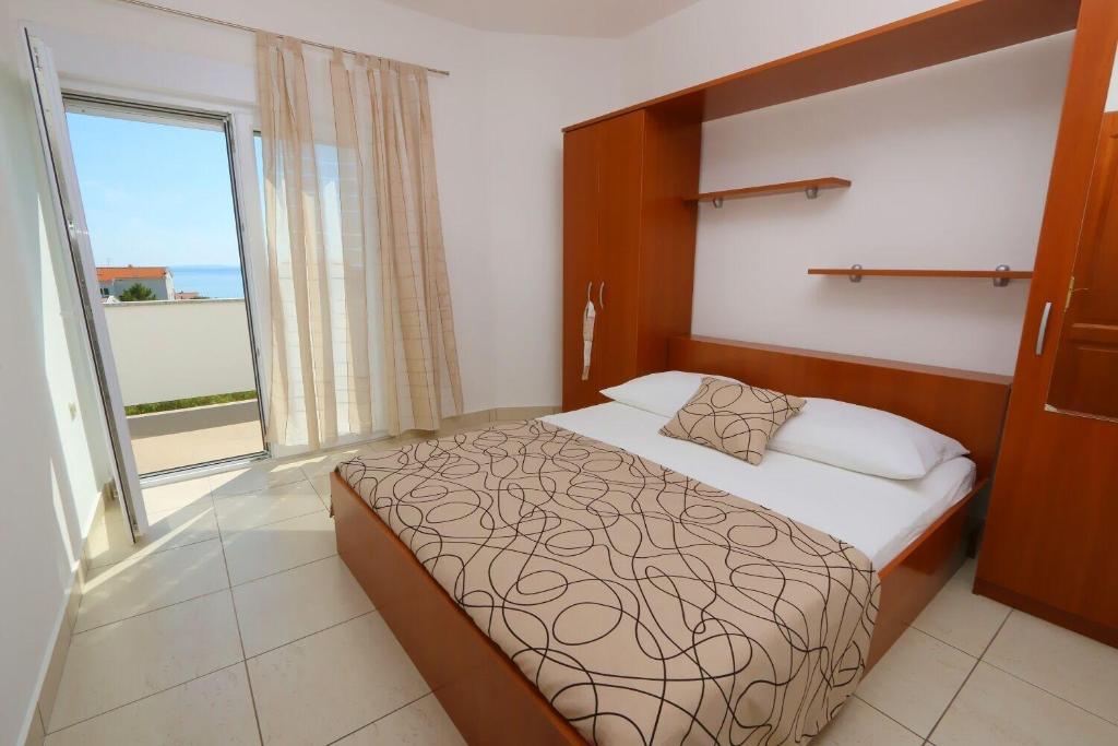 sypialnia z łóżkiem i dużym oknem w obiekcie Apartments Boris w Novalji