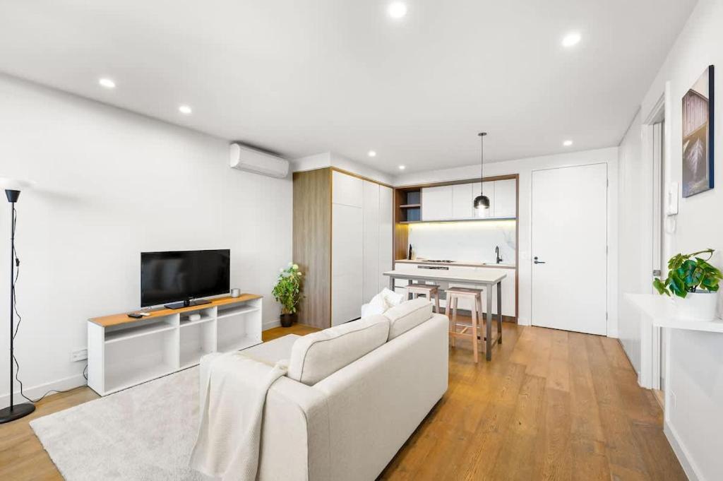 a living room with a white couch and a tv at Perfectly Located Executive 1BR at Caulfield North in Melbourne