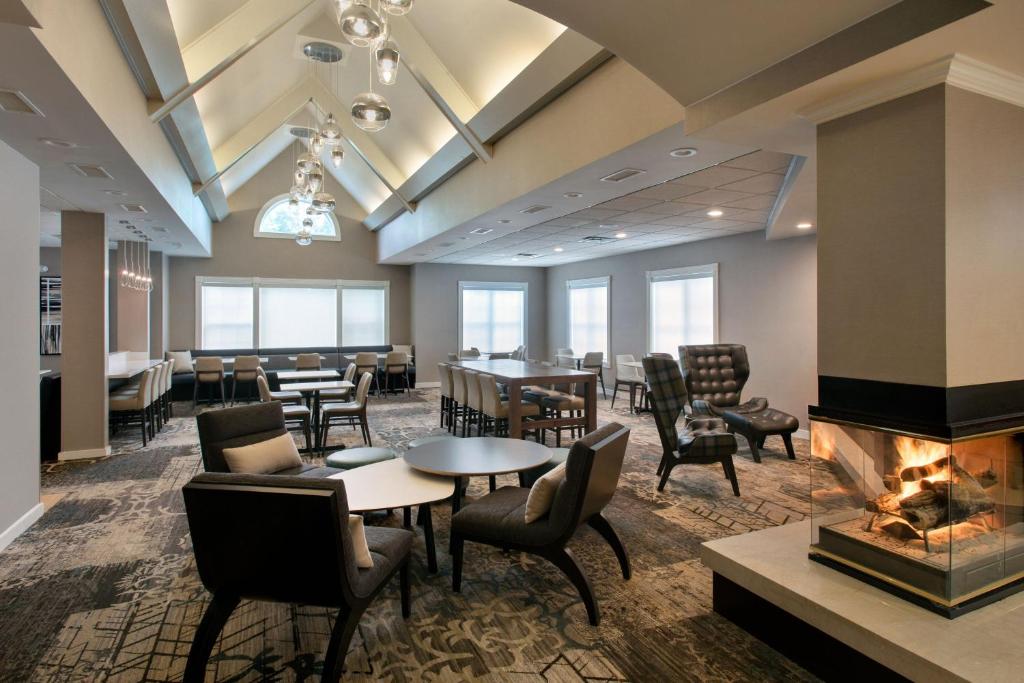a restaurant with tables and chairs and a fireplace at Residence Inn Hartford Manchester in Manchester