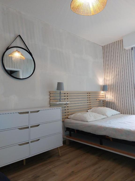 une chambre avec un lit et un miroir au mur dans l'établissement T2 Esplanade de la Mer, à Saint-Hilaire-de-Riez