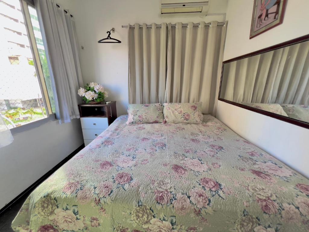 a bedroom with a bed with a floral bedspread at Ponto do Paraíso - Quarto inteiro em apartamento compartilhado in Fortaleza