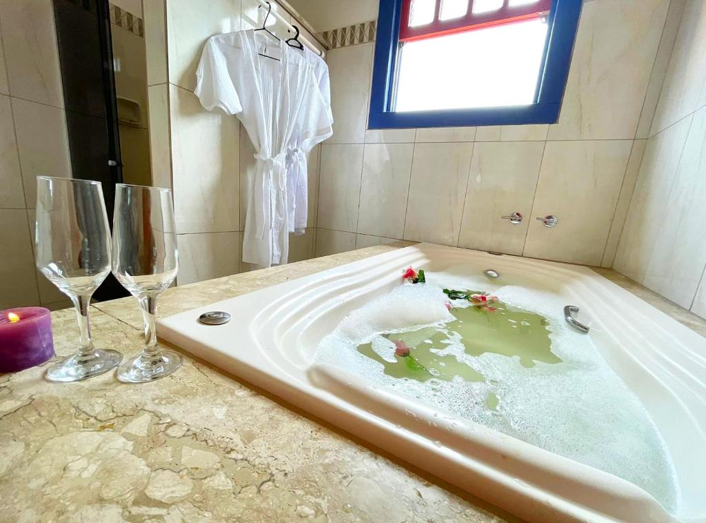 um banheiro com banheira e duas taças de vinho em Pouso Aconchego - 350m Maria Fumaça em Tiradentes