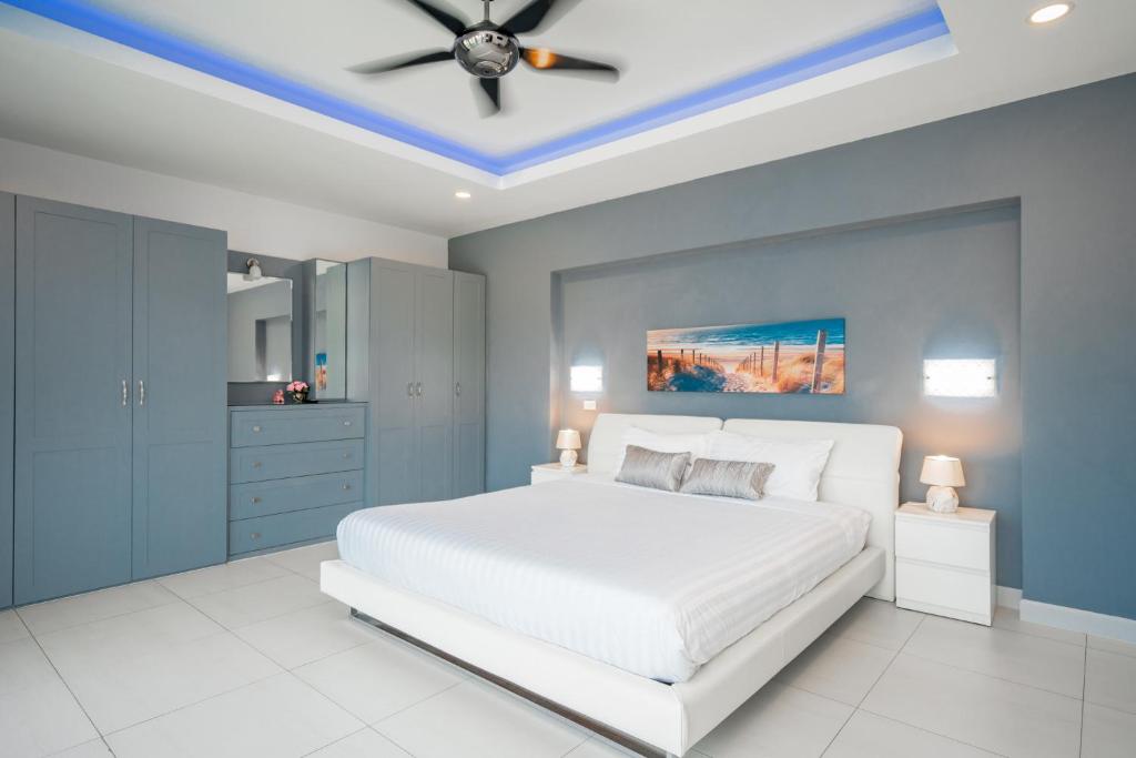 a bedroom with a white bed and a ceiling fan at Luxury 4 Bedroom Beach House in Ban Saiyuan (1)