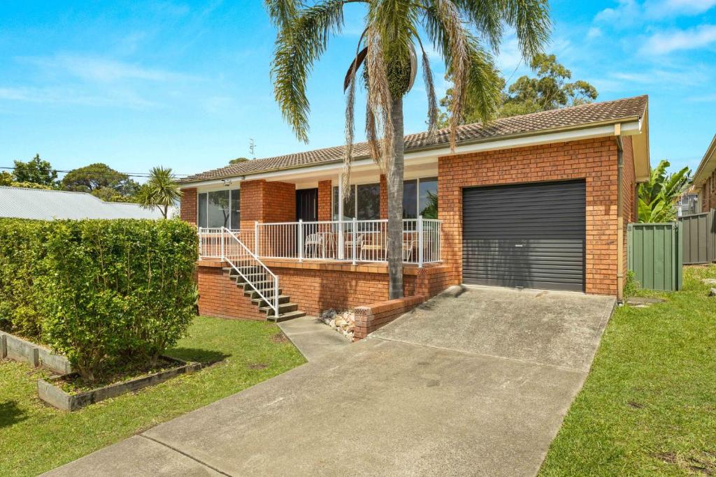 ein Backsteinhaus mit Garage und Palmen in der Unterkunft Tide's Edge by Experience Jervis Bay in Vincentia