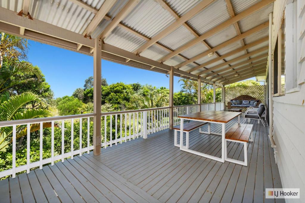 una terraza con una mesa y un banco en ella en Classic Beach House on Surfside - Pet Friendly, en Pottsville