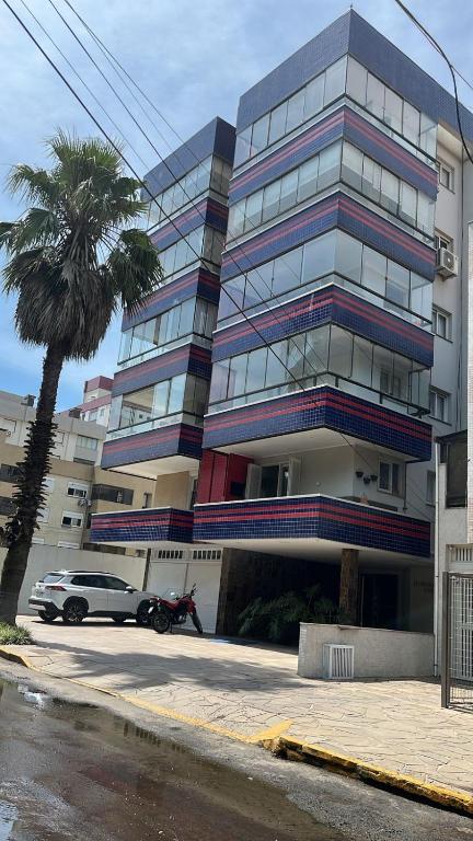 a building with a car parked in front of it at Espaçoso 1 d perto do mar com vaga in Capão da Canoa