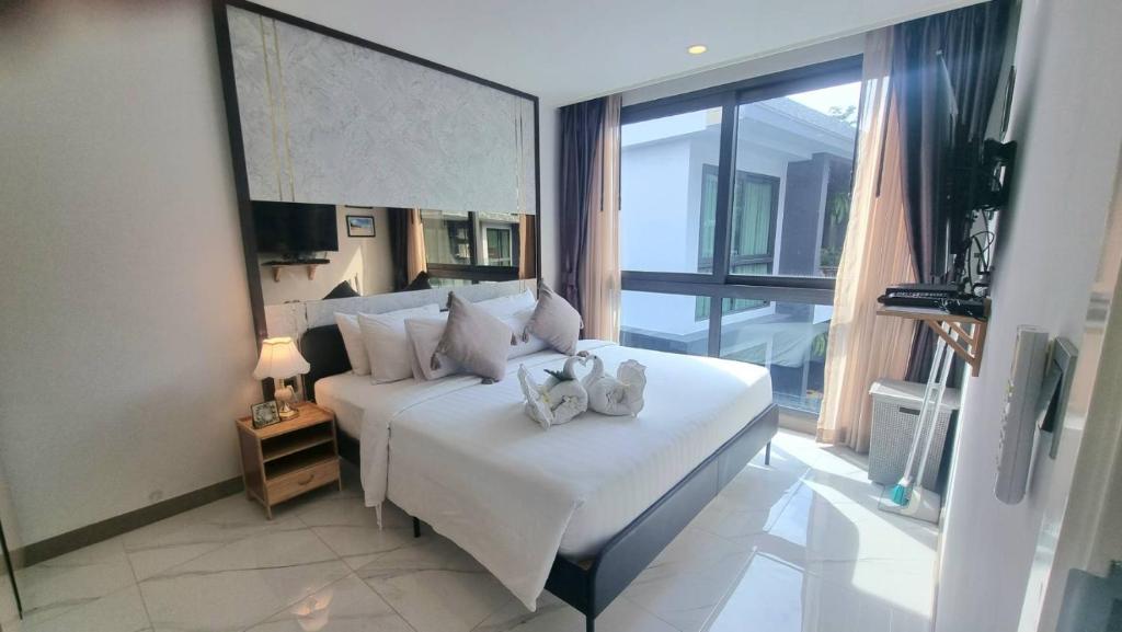 una camera da letto con un grande letto bianco e una grande finestra di B506-top Floor Pool View 1 Br At Ao Nang Beach ad Aonang Beach