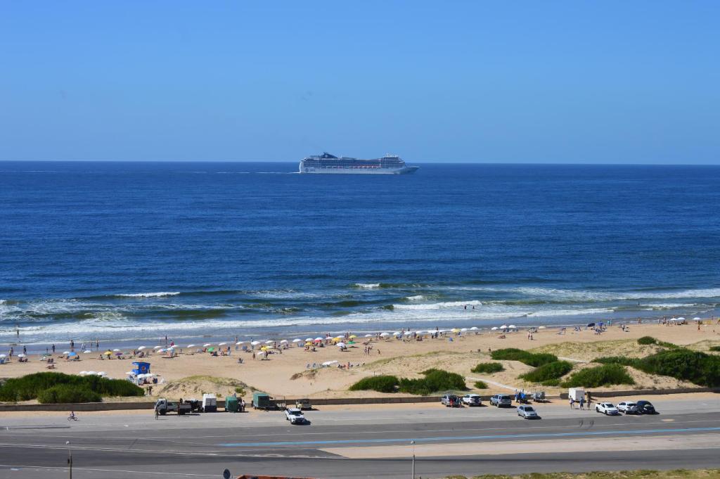 un groupe de personnes sur une plage avec un bateau de croisière dans l'océan dans l'établissement Arenas del mar, à Punta del Este