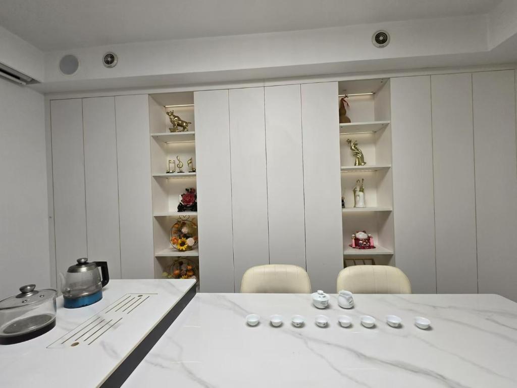 a white kitchen with a dining table and chairs at Cloud&Sea Inn in Shenzhen