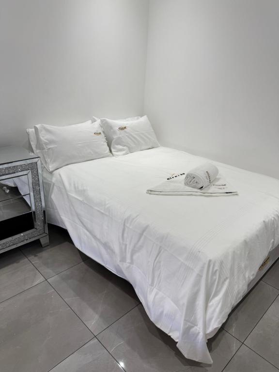 un letto con lenzuola bianche e un cappello sopra di The Zebra a Gqeberha