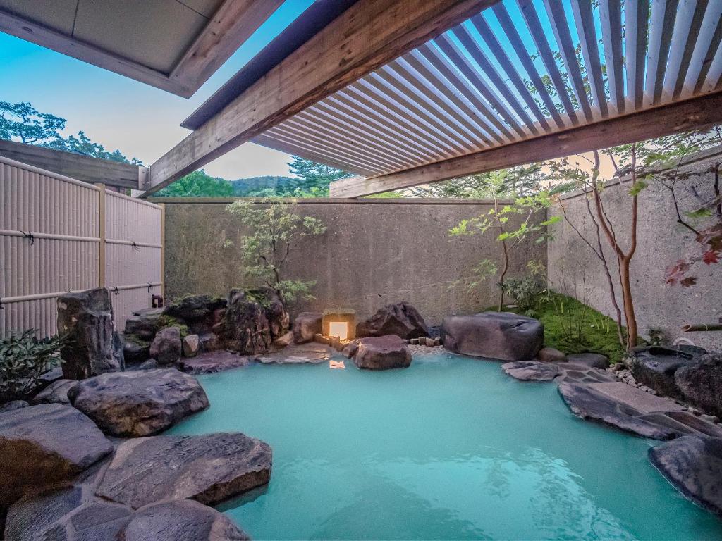 a pool of water with rocks in a garden at Hotel Hanaan in Nikko