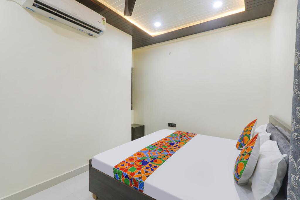 una camera da letto con un letto bianco e una coperta colorata di FabExpress Awadh Inn - 400m from Shri Ram Janam Bhumi a Ayodhya
