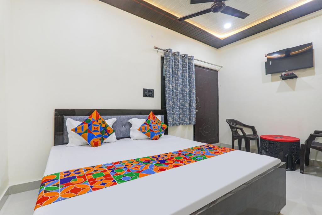 una camera da letto con un grande letto bianco con cuscini colorati di FabExpress Awadh Inn - 400m from Shri Ram Janam Bhumi a Ayodhya