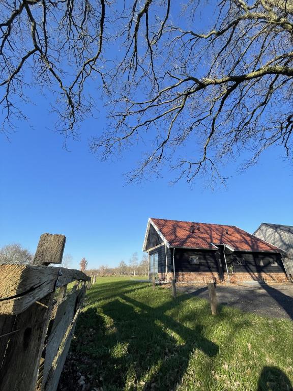 an old barn in a field with a fence at Het Bruineveld in Daarle