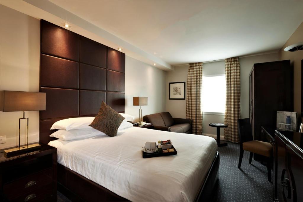 a hotel room with a large bed and a chair at Stamford Bridge Hotel London in London