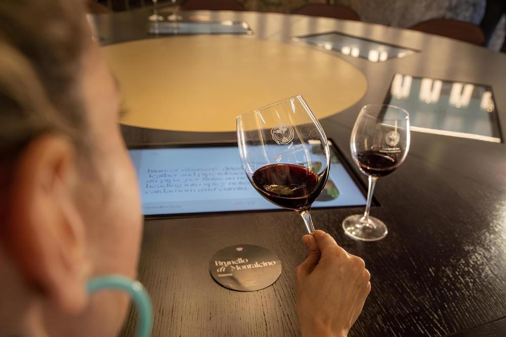 a person holding a glass of wine on a table at Perla moderna nella natura in Siena