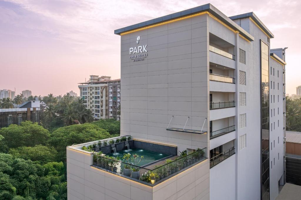 a building with a swimming pool on top of it at Park Inn & Suites by Radisson Thrissur East Fort in Trichūr