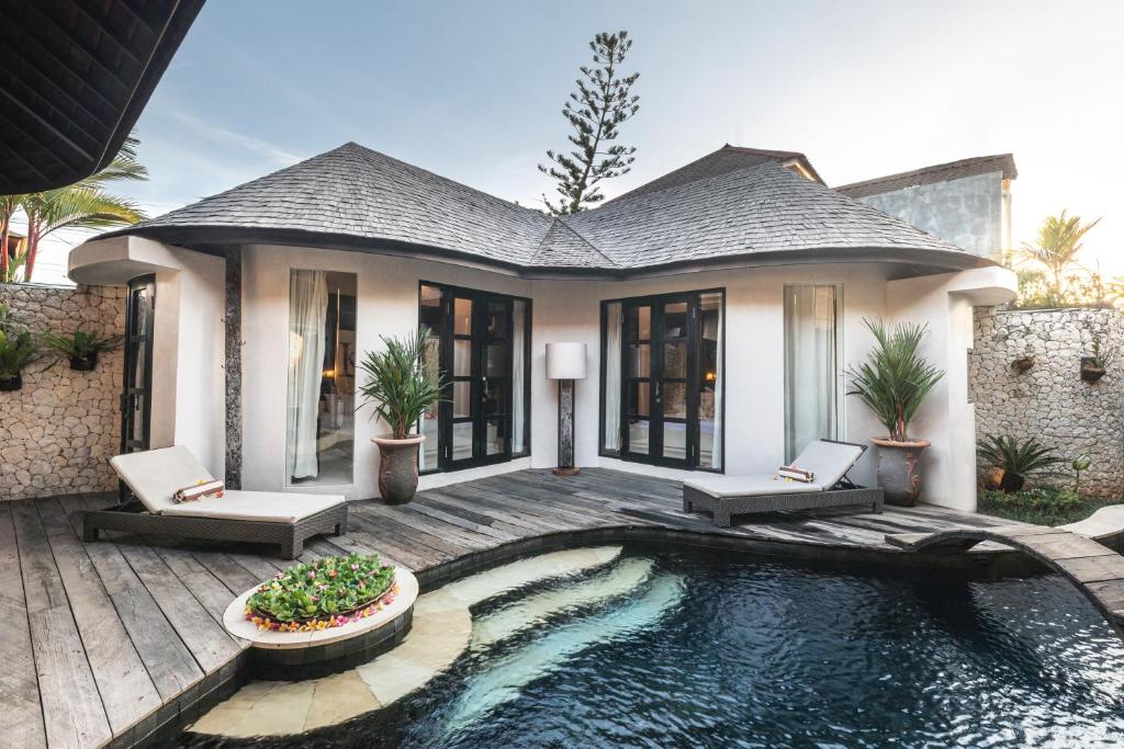 a house with a swimming pool in front of a house at Sandi Kala Villas in Kerobokan