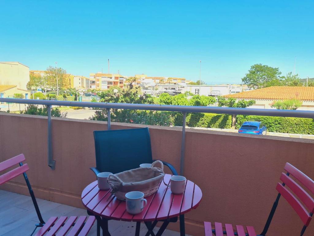 une table avec un panier sur un balcon avec deux chaises dans l'établissement Appartement 2 pièces cabine CAP D'AGDE CT045-151, au Cap d'Agde