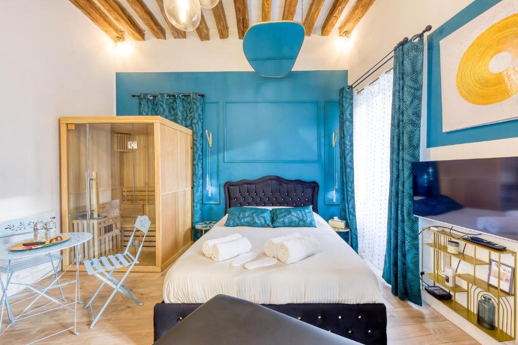 1 dormitorio con paredes azules y 1 cama con toallas en Suite bien être - jacuzzi et sauna / love room, en Arpajon