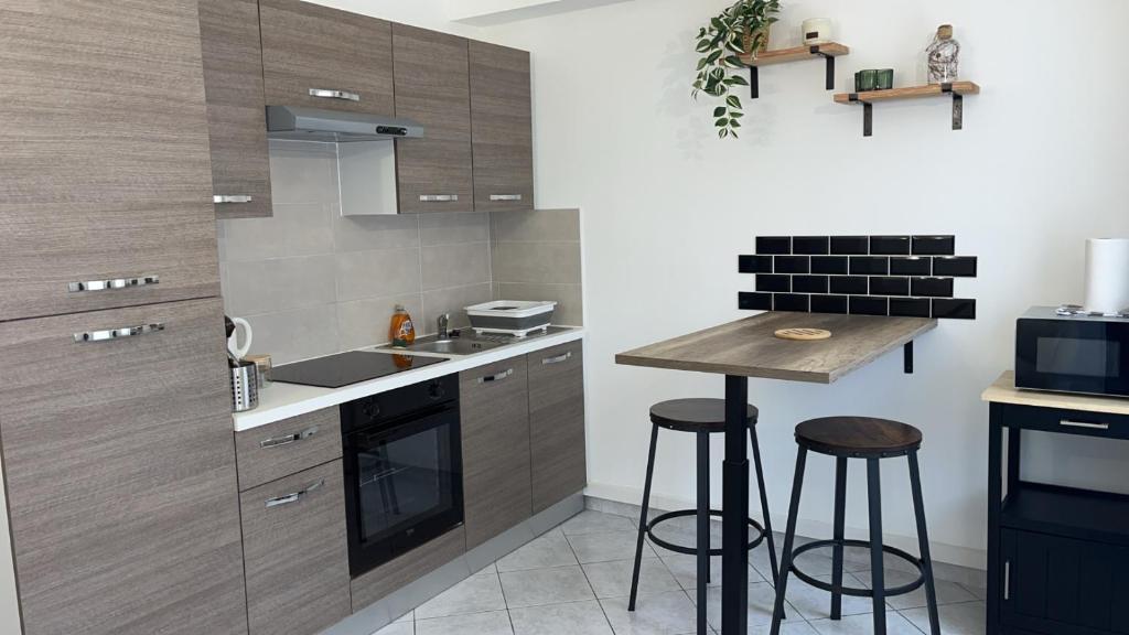 a kitchen with wooden cabinets and a small island with stools at Gîte Le Studio 7 in Sully-sur-Loire