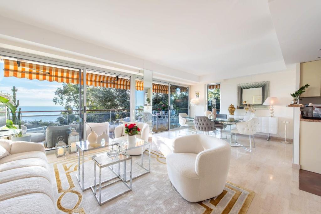 un salon avec des meubles blancs et une grande fenêtre dans l'établissement Côte d’Azur Sea View Tennis Beach Access, à Vallauris