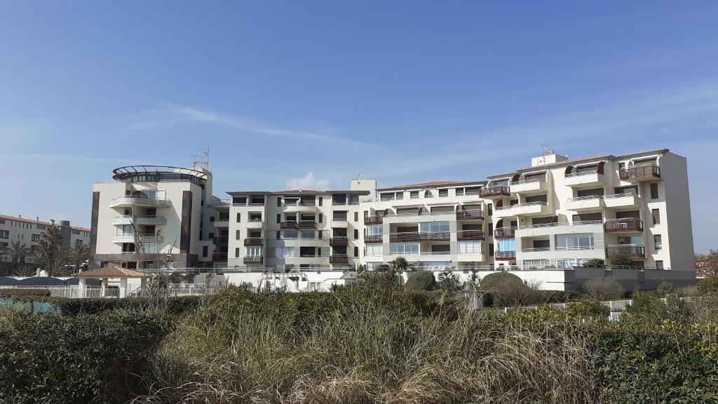 duży biały apartamentowiec na plaży w obiekcie SUNSET Joli T2 vue mer piscine SUNSET Cap d'Agde w Cap d'Agde