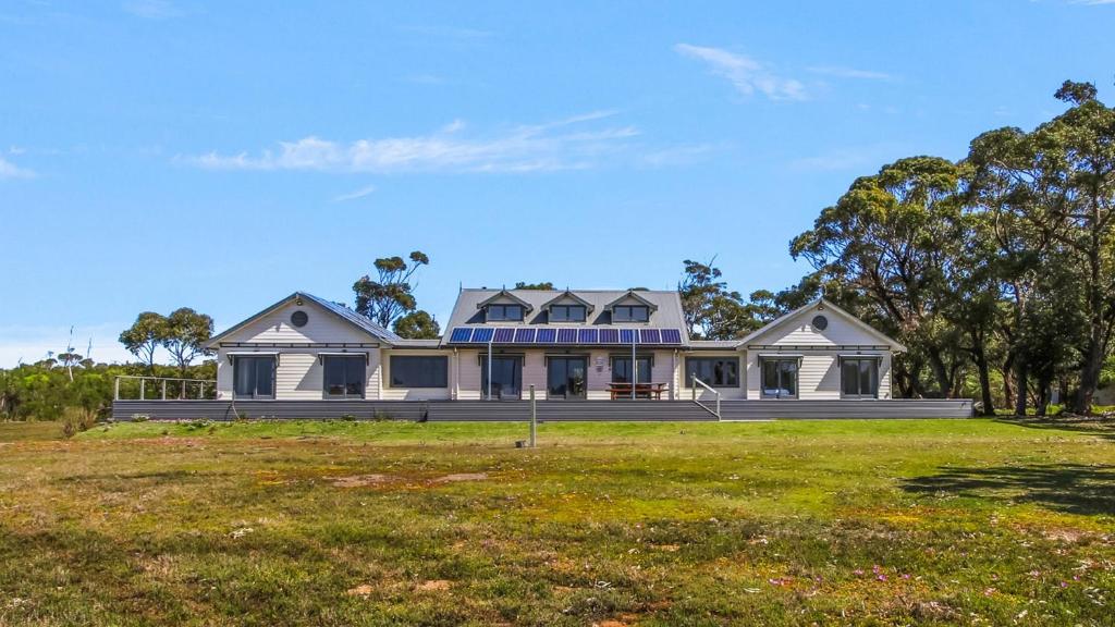 a large white house on a grass field at Peninsula at Metung House - Boat Access Only Getaway in Metung