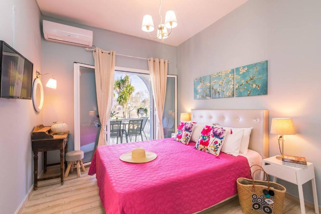 a bedroom with a pink bed with a hat on it at Lamda Apartments By Estia in Roda